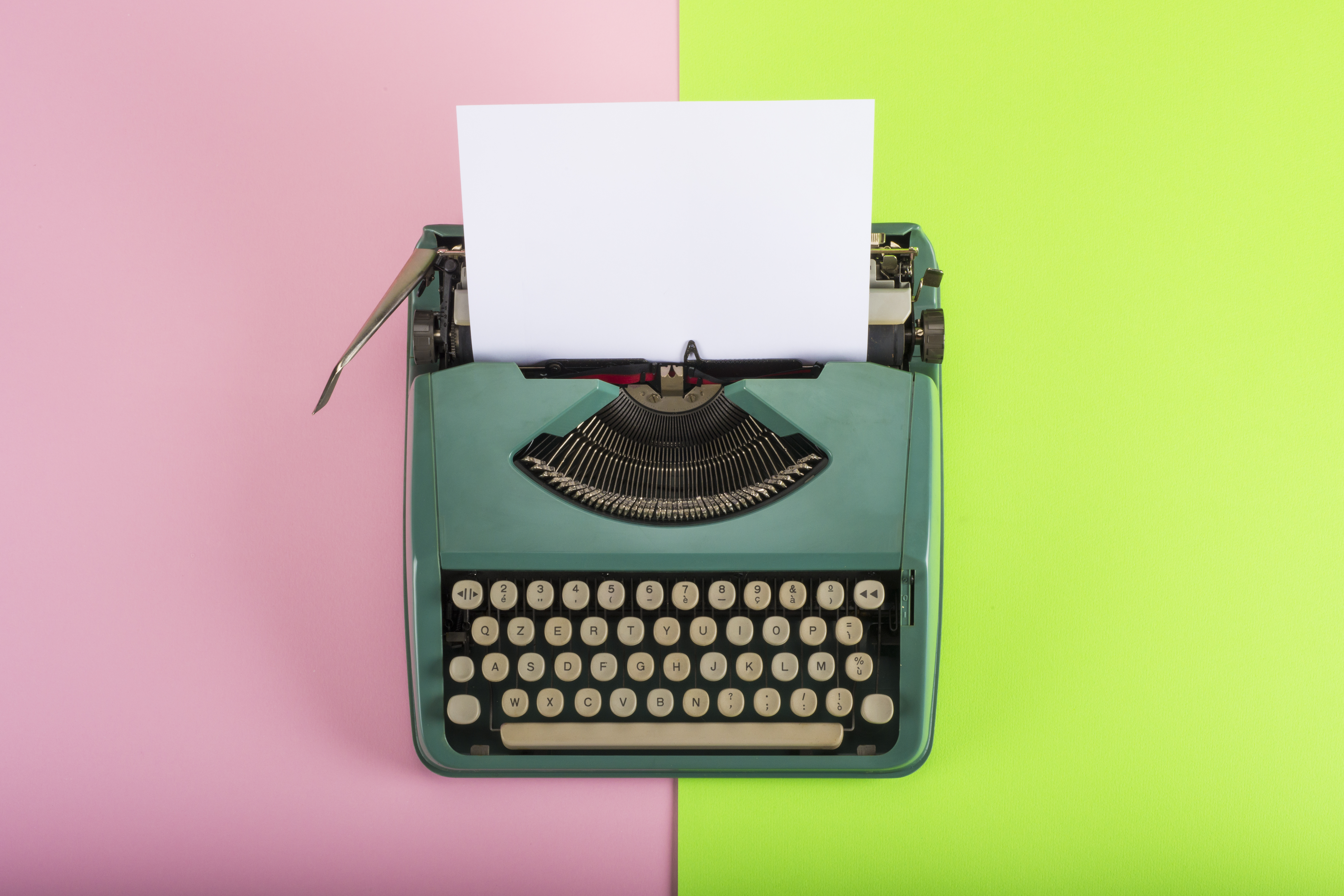 Vintage typewriter with paper sheet on pink and green background